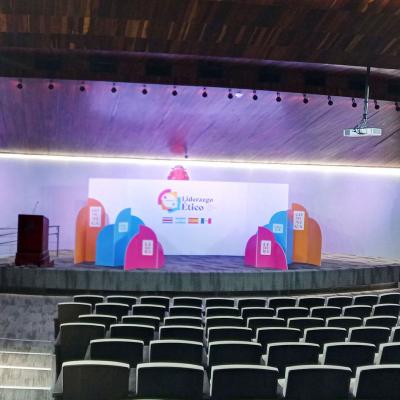 Un escenario con una pantalla y sillas delante.