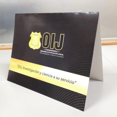 Una tarjeta negra y dorado con el logo tipo del OIJ