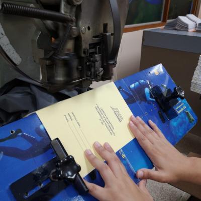 Persona trabajando en una maquina de encuadernado.